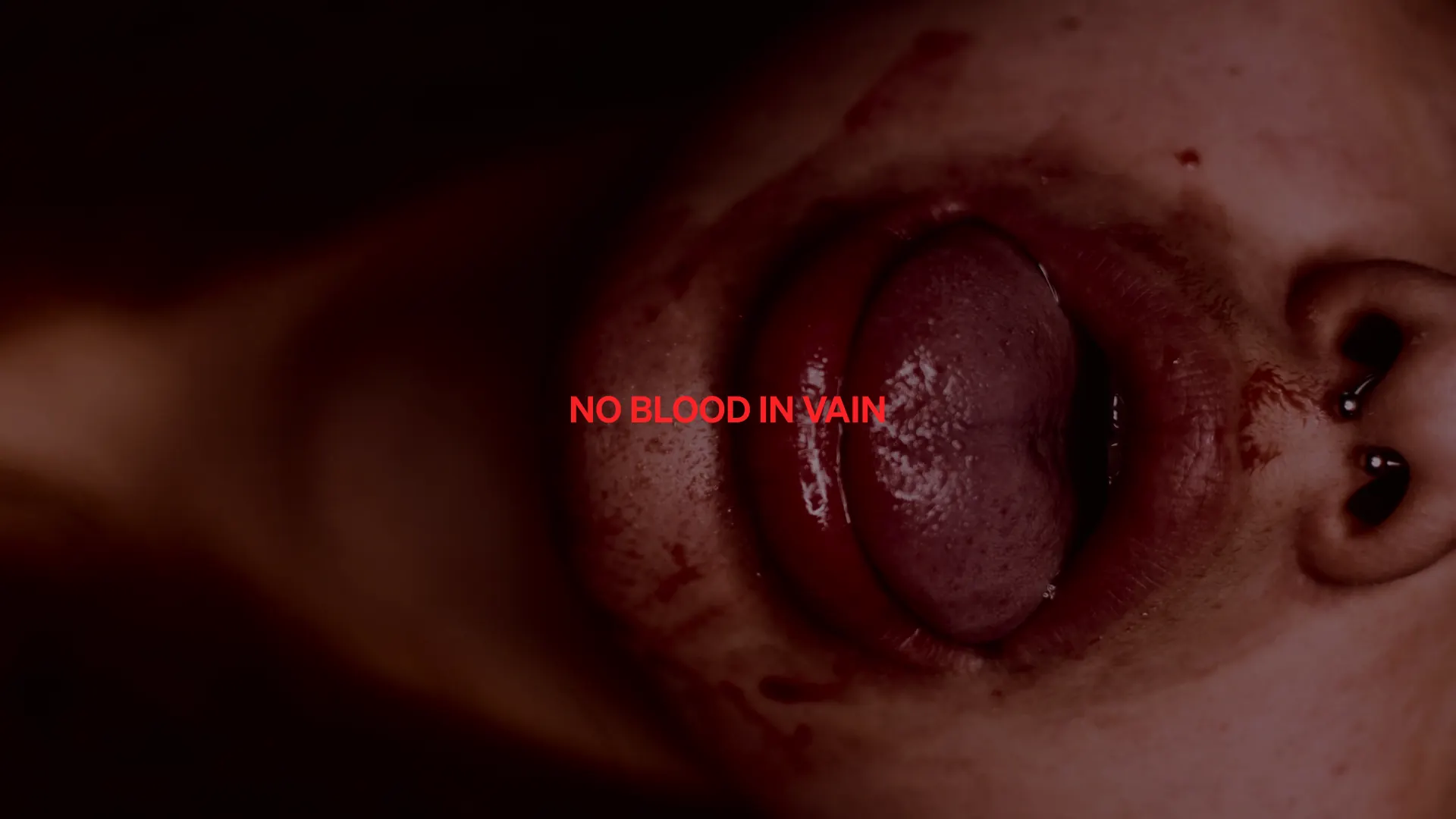 Close-up of blood-red lips parted around a tongue: No Blood in Vain